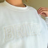 A women's embroidered crewneck sweatshirt with the word "Bride" elegantly stitched on the front. This soft and comfortable white sweatshirt is perfect for the bride-to-be as she prepares for her big day. Available in unisex sizes Small to Extra Large, made from a preshrunk 50/50 cotton and polyester blend.